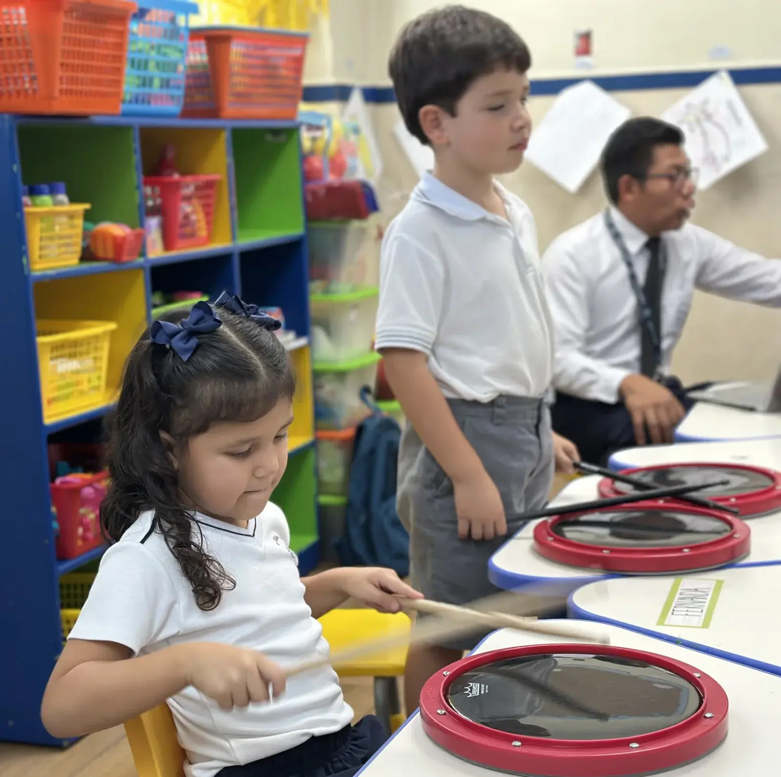 Maestra interactúa con alumna en aula colorida durante actividad educativa en Instituto Cumbres.