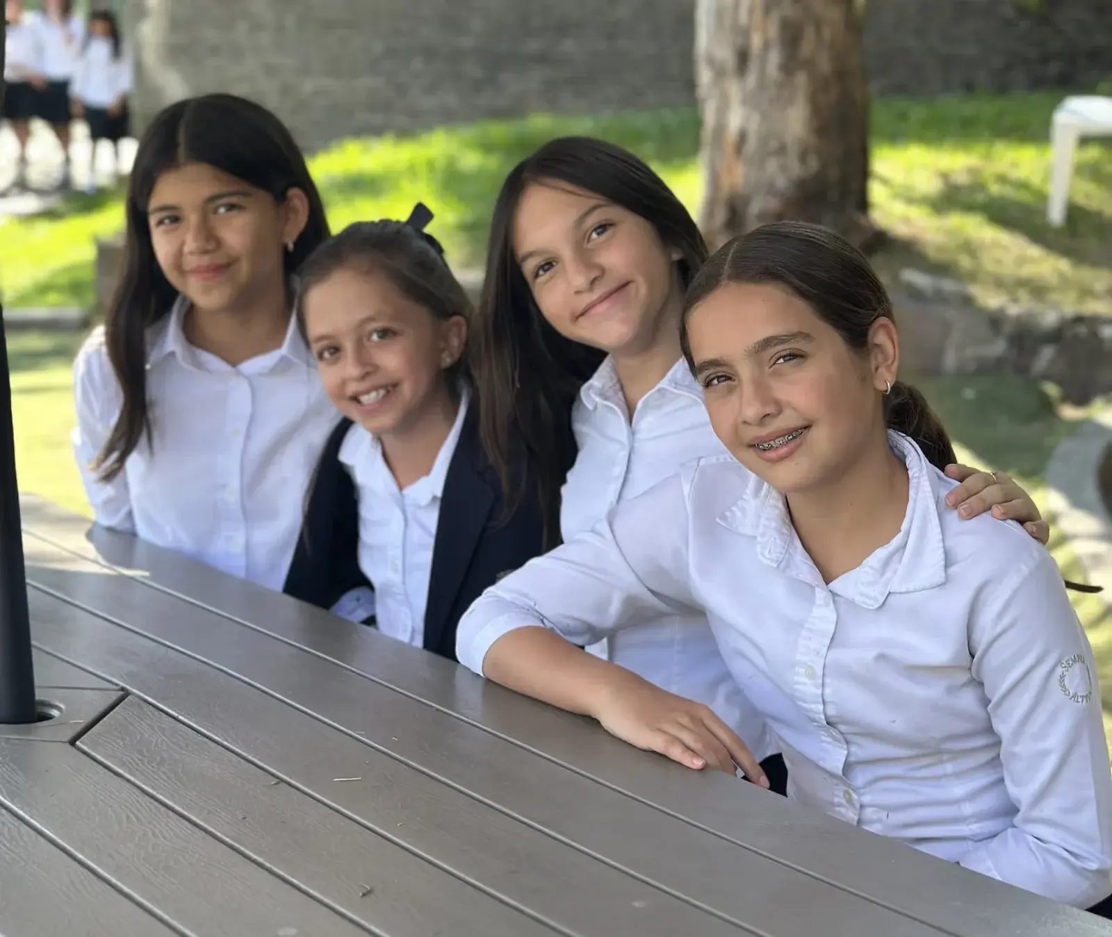 Estudiantes en uniforme escolar realizando una actividad colaborativa de dibujo y pintura en el aula con materiales creativos.